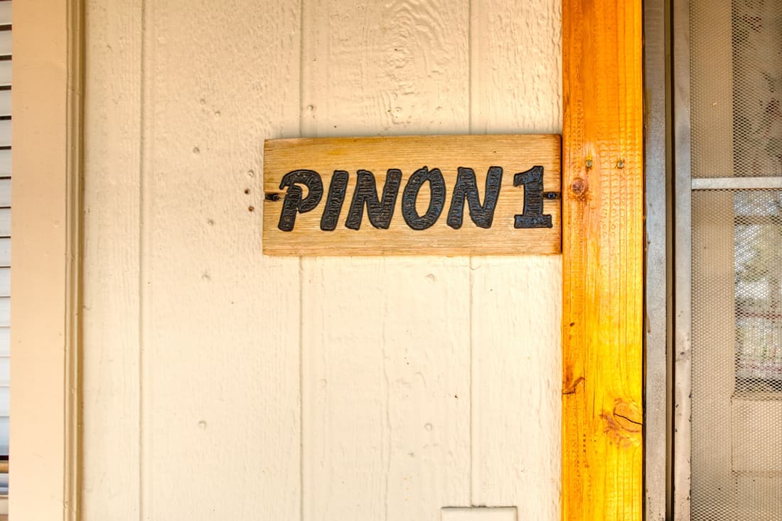 The hand-painted Pinon 1 sign on the cottage door